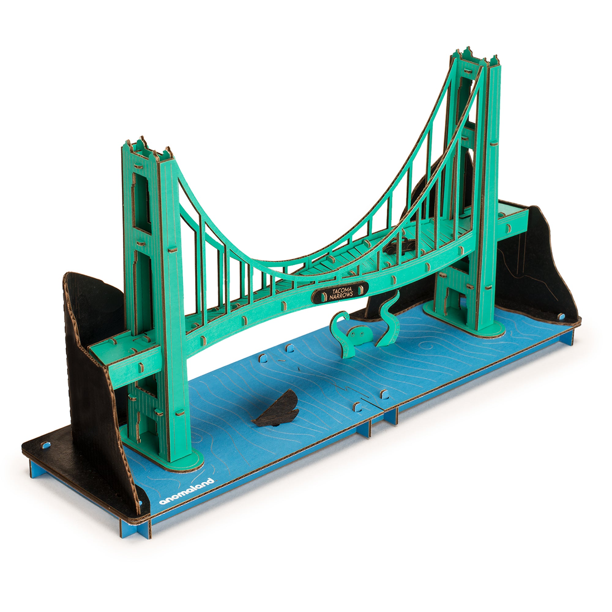 Anomaland Tacoma Narrows 1940 Bridge Cardboard Model Kit - assembled. Green twisting bridge on a base of blue water with black hills in the background.